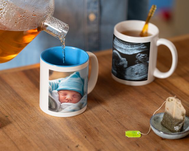 Del tè viene servito in una tazza personalizzata con la foto di un neonato accanto a una tazza con un'immagine dell'ecografia.