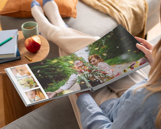 Donna che guarda un fotolibro aperto con rilegatura piatta con foto di matrimonio.